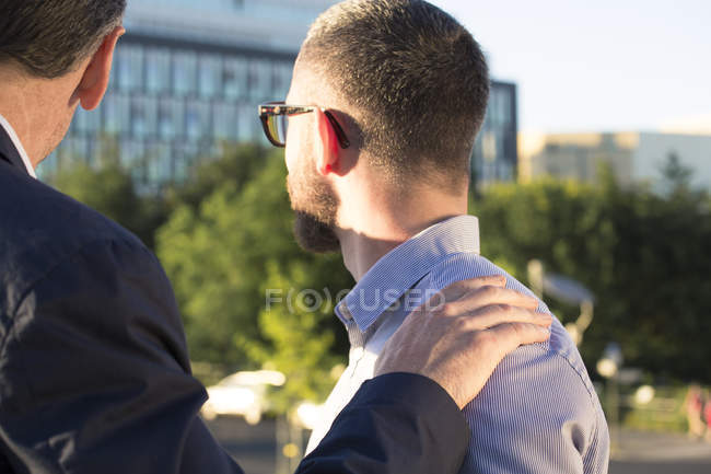Älterer Geschäftsmann legt Hand auf die Schulter eines jüngeren Geschäftsmannes — Stockfoto