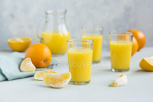 Vasos de zumo de naranja recién exprimido y rodajas de naranja - foto de stock