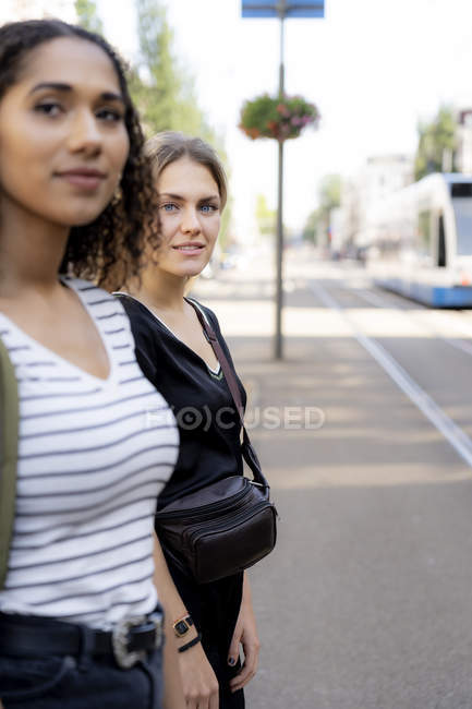 Two young women crossing street in the city — Stock Photo