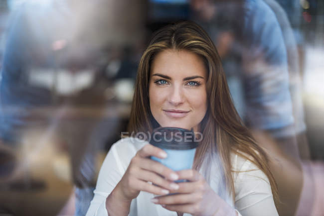 Портрет усміхненої молодої жінки за вікном з кавою — стокове фото