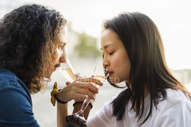 Молода пара п'є шампанське на березі річки — стокове фото