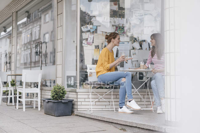 Due amiche che si incontrano in una caffetteria e parlano — Foto stock