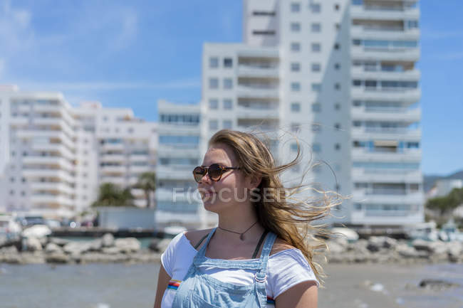 Jovem mulher na praia, usando óculos de sol, retrato — Fotografia de Stock