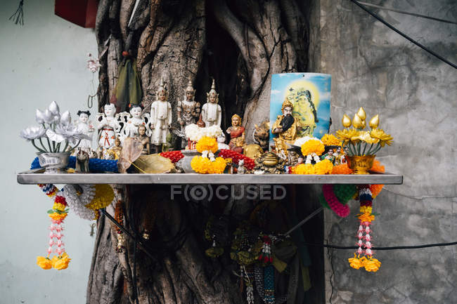 Tailândia, Bangkok, Altar com figuras religiosas budistas em uma árvore — Fotografia de Stock