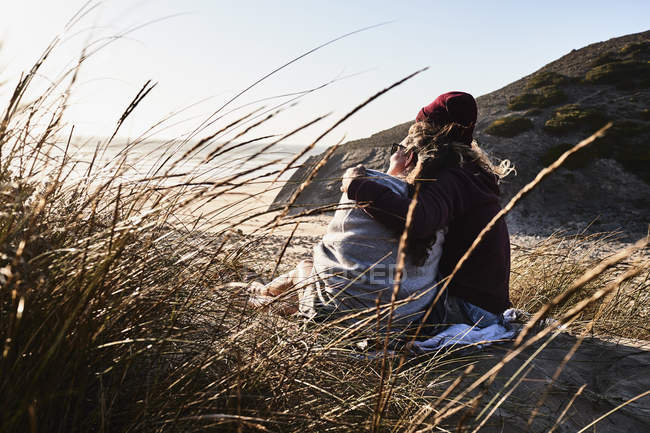 Португалія, Алгарве, романтична пара сидячи на пляжі на заході сонця — стокове фото