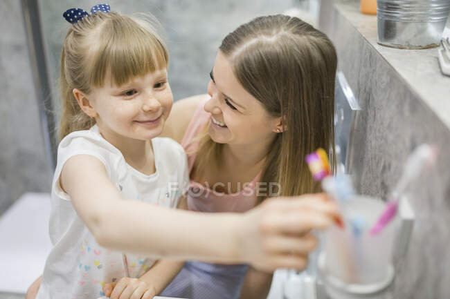 Madre e figlia spazzolatura denti in bagno — Foto stock