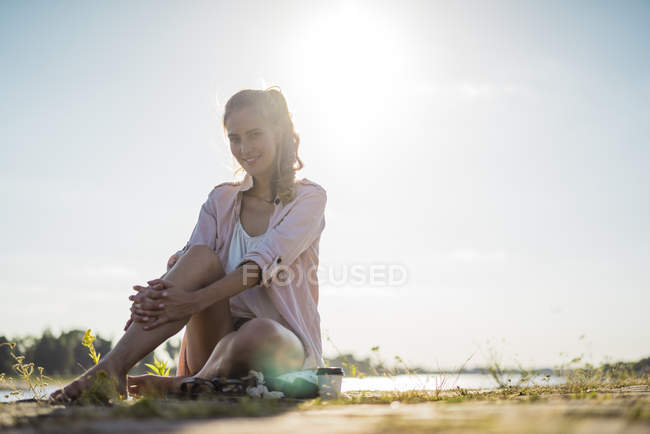 Ritratto di donna sorridente seduta sul lungofiume in estate — Foto stock