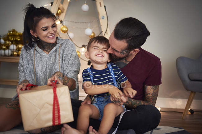 Feliz niño abriendo regalo de Navidad con sus padres en casa — Stock Photo