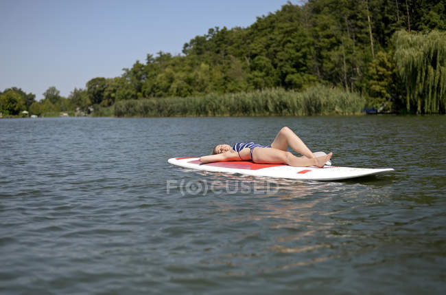 Germany, Brandenburg, woman relaxing on paddleboard on Zeuthener See — Stock Photo