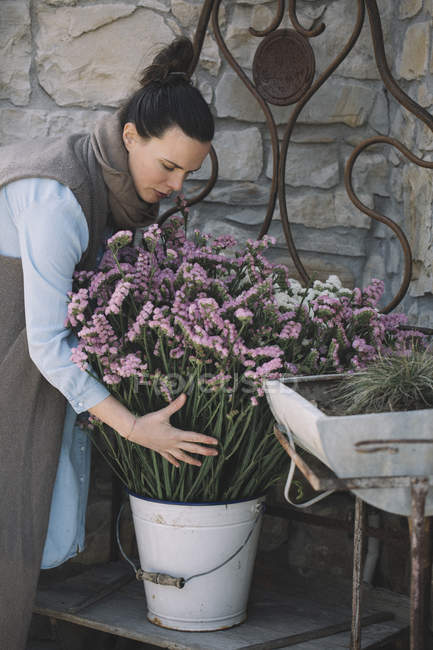 Woman arranging fresh flowers in metal bucket — Stock Photo