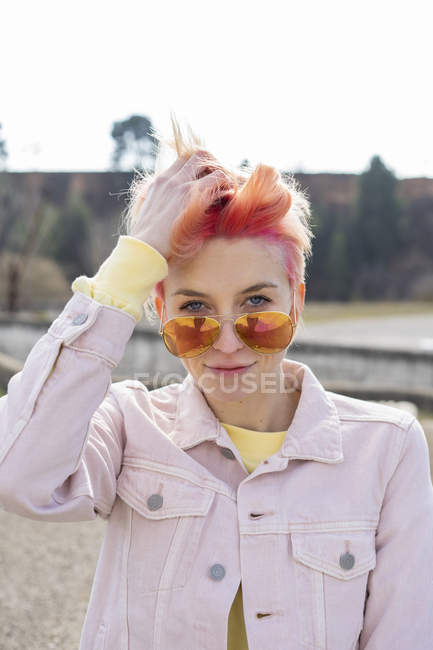 Portrait of young woman, sun glasses and pink jeans jacket — Stock Photo