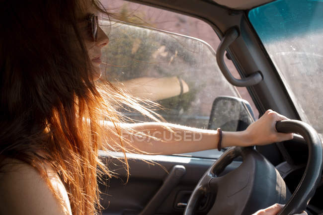 Young woman with windswept hair driving a car — Stock Photo