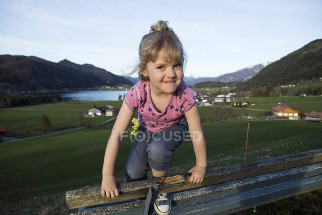 Austria, Tirol, Walchsee, chica feliz en un banco - foto de stock