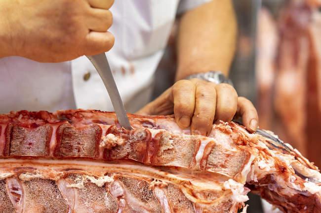Butcher cutting up pork — Stock Photo