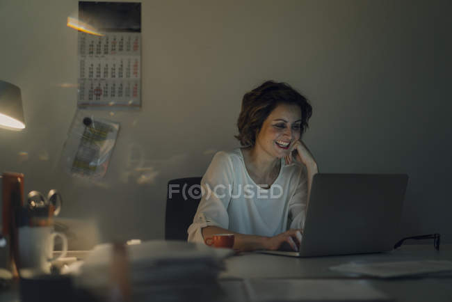 Donna d'affari che fa gli straordinari, utilizzando il computer portatile — Foto stock