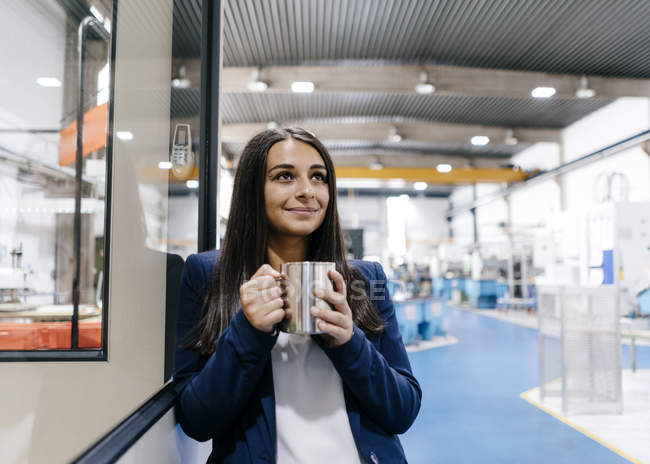 Впевнена жінка, що працює на високотехнологічному підприємстві, п'є каву — стокове фото