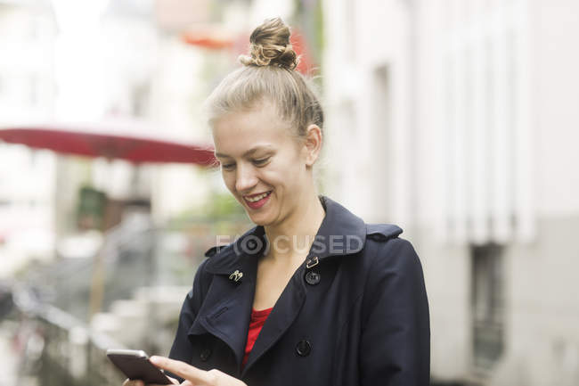 Portrait of smiling young man looking at cell phone — Stock Photo