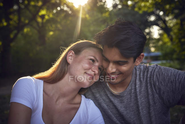 Romantic young couple sitting in park, enjoying sunset — Stock Photo