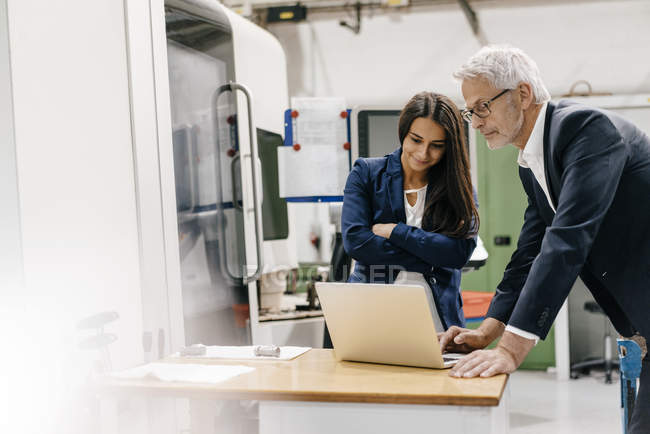 Businessman and businesswoman in high-tech enterprise, having a meeting, using laptop — Stock Photo