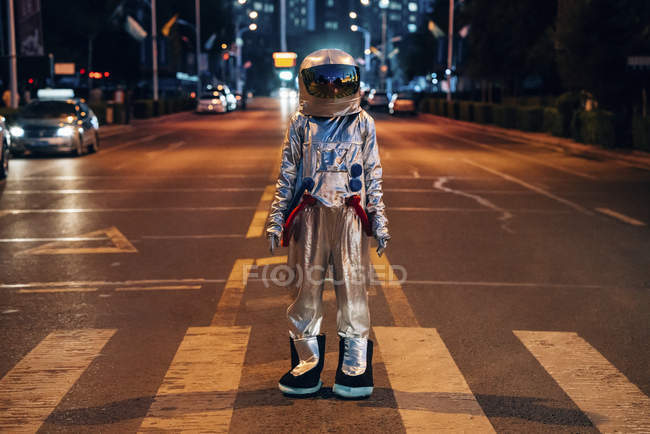 Spaceman standing on street in city at night — Stock Photo