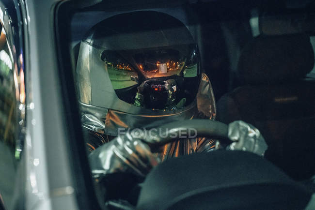 Close-up of spaceman driving car at night — Stock Photo
