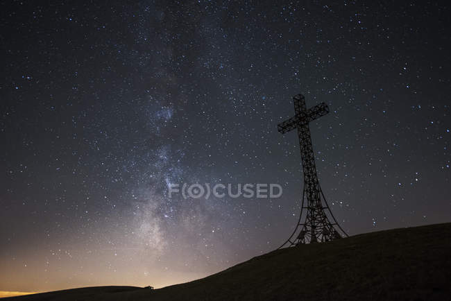 Italia, Marcas, silueta de la cruz de la cumbre en Monte Catria por la noche - foto de stock