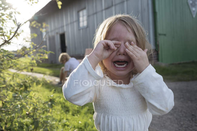 Portrait of screaming little girl covering eyes with her hands — Stock Photo
