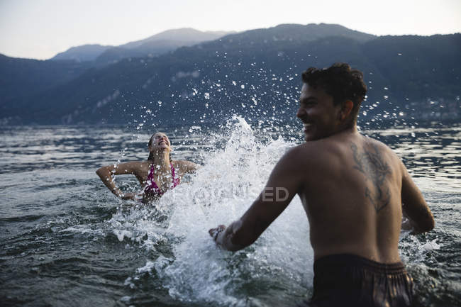 Happy young couple playing in a lake — Stock Photo