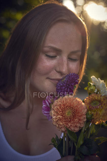 Giovane donna mazzo profumato di fiori ad occhi chiusi — Foto stock
