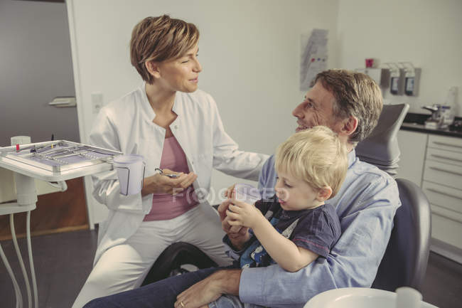 Dentista donna che parla con paziente con figlio seduto sulle sue ginocchia — Foto stock
