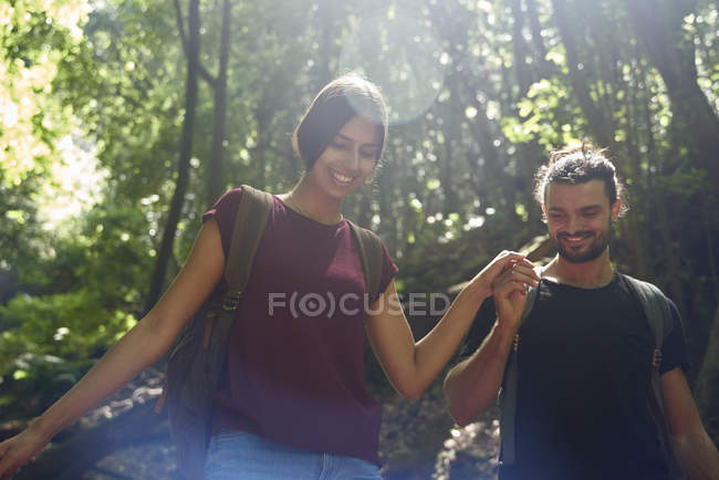 Sorrindo casal andando de mãos dadas através de uma floresta — Fotografia de Stock