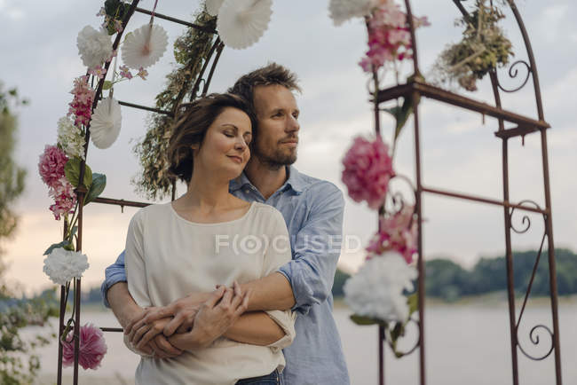 Happy couple embracing under wedding arch — Stock Photo