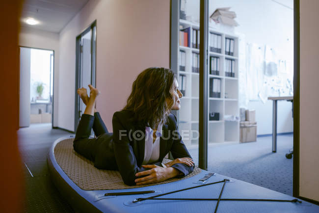 Barefoot Businesswoman laying on sup paddle board, daydreaming in office —  indoors, person - Stock Photo | #270453824
