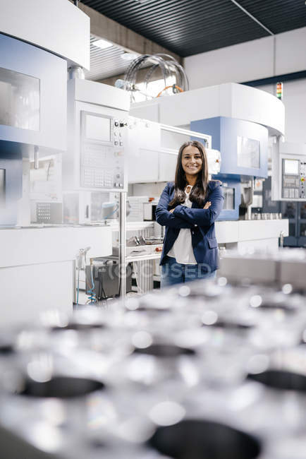 Confident woman working in high-tech enterprise, standing in factory workshop with arms crossed — Stock Photo