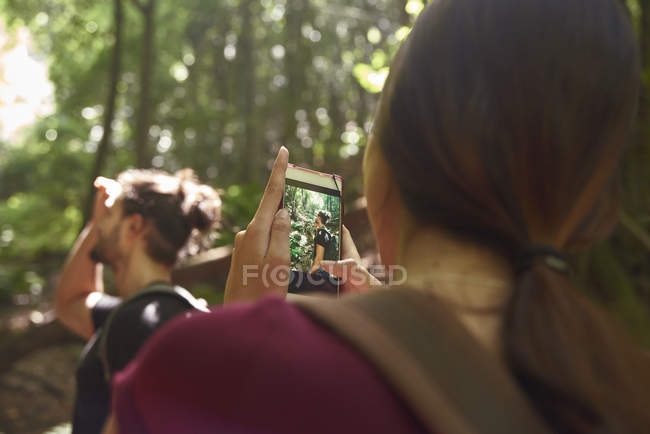 Frau fotografiert mit Handy ihres Freundes im Wald — Stockfoto