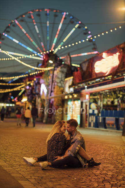 Glückliches junges Paar umarmt und küsst sich auf einem Jahrmarkt — Stockfoto