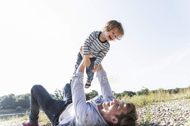 Father and son having fun at riverside, playing aeroplane — Stock Photo