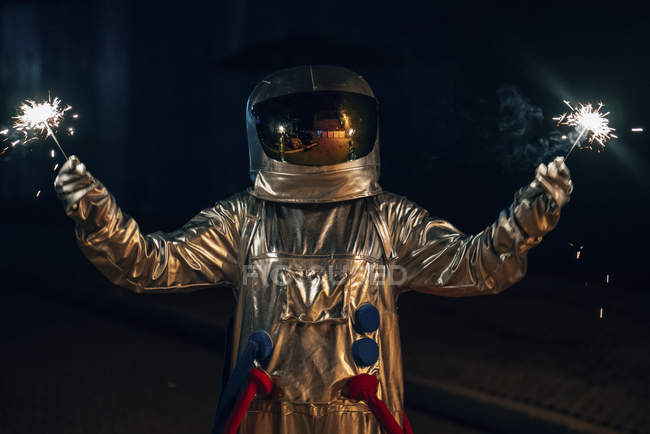 Spaceman de pie en la carretera por la noche y la celebración de bengalas - foto de stock