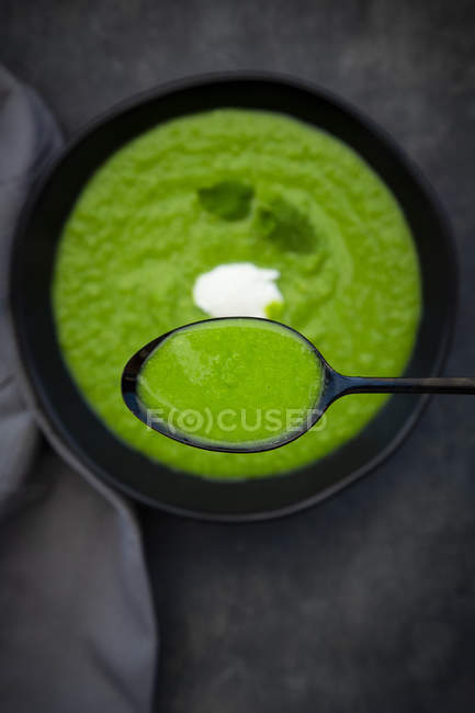 Spoon and bowl of pea mint soup — Stock Photo