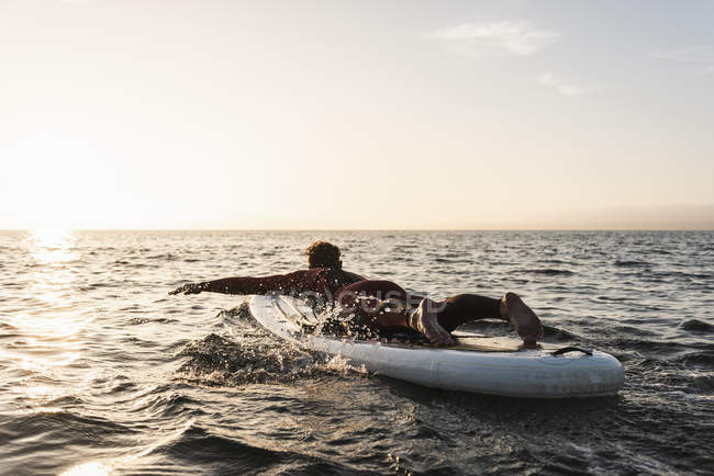 Young man on paddleboard at sunset — Stock Photo