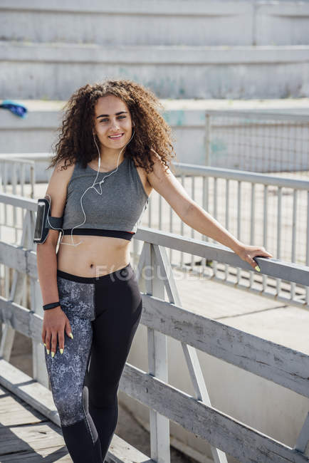 Portrait de jeune femme sportive souriante portant des écouteurs — Photo de stock