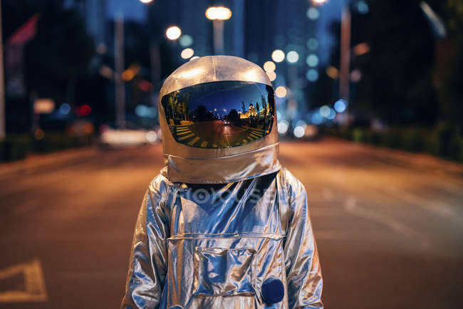 Космонавт, стоящий на улице в городе ночью — стоковое фото