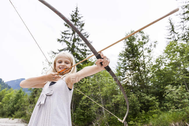 Улыбающаяся девушка с луком и стрелами в природе — стоковое фото