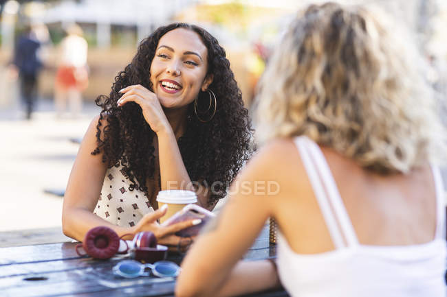 Happy female friends talking together at table outdoors — Stock Photo