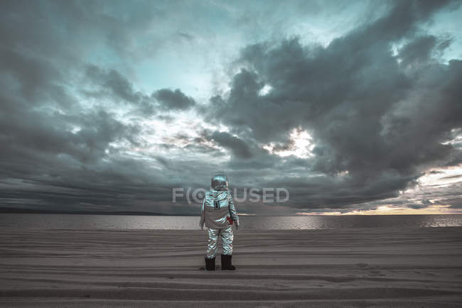 Lonely spaceman looking at lake on nameless planet — Stock Photo