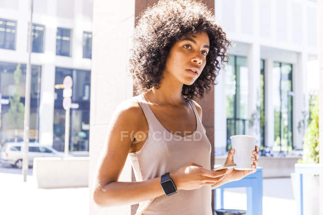 Ritratto di giovane donna pensierosa con caffè da portare via e cellulare — Foto stock