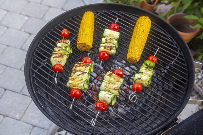 Grilled vegetarian grill skewers, tomato, sheep cheese and zucchini slices, corn cobs on grill — Stock Photo