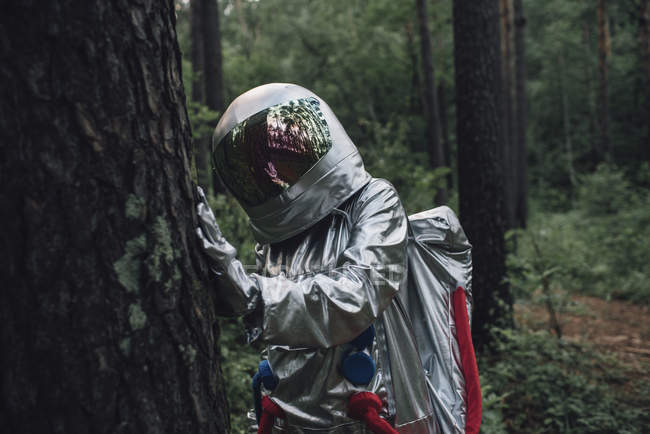 Spaceman examining tree trunk in forest — Stock Photo