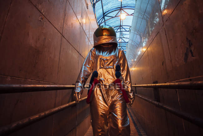 Spaceman in city at night walking in narrow passageway — Stock Photo