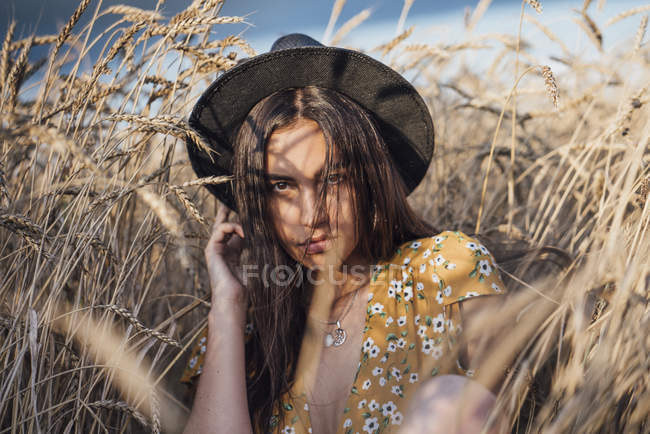 Portrait de jeune femme portant un chapeau posant dans un champ de maïs — Photo de stock